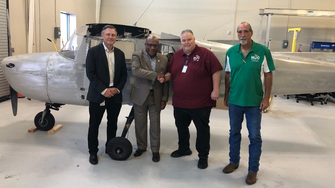 HCC officials stand in front of a Cessna 150 plane.